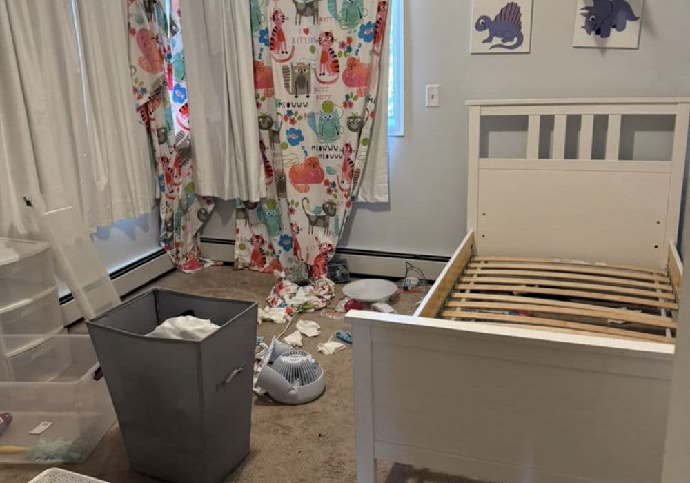 Messy children's bedroom with an unmade bed, cluttered floor, and colorful curtains.